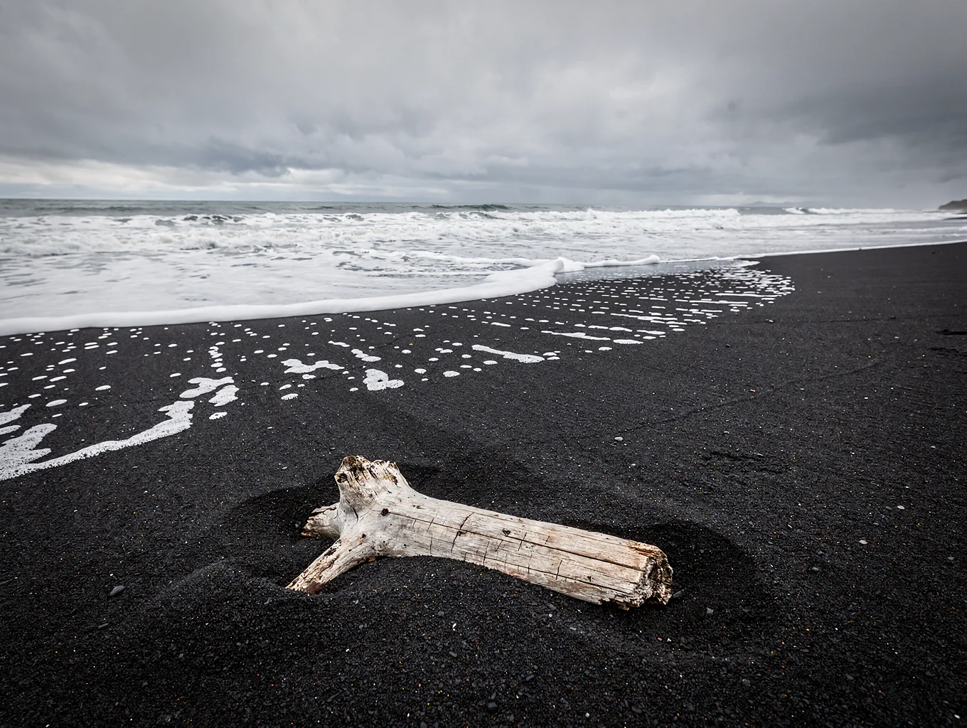 Glacial ice fragments resting on black basalt volcanic sand in Iceland