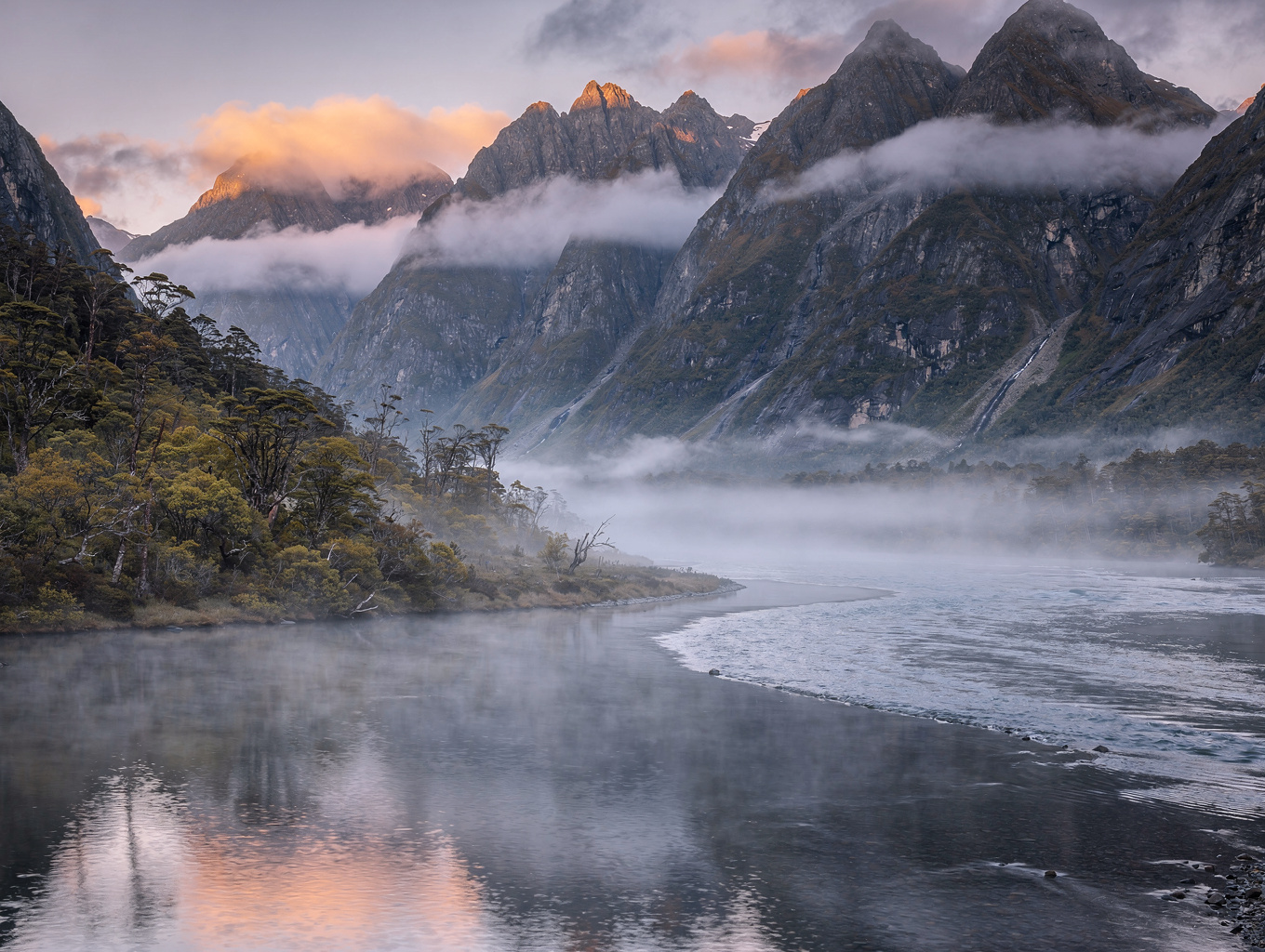 Steep fjord cliffs enveloped in mist over deep alpine waters in New Zealand